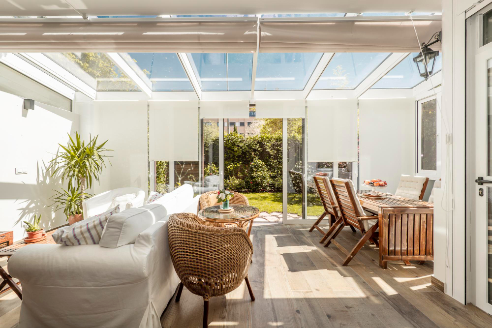 terrace-with-access-garden-with-white-aluminum-carpentry-glass-with-large-sliding-doors-with-light-wooden-floors-wicker-furniture-large-white-sofa (1)