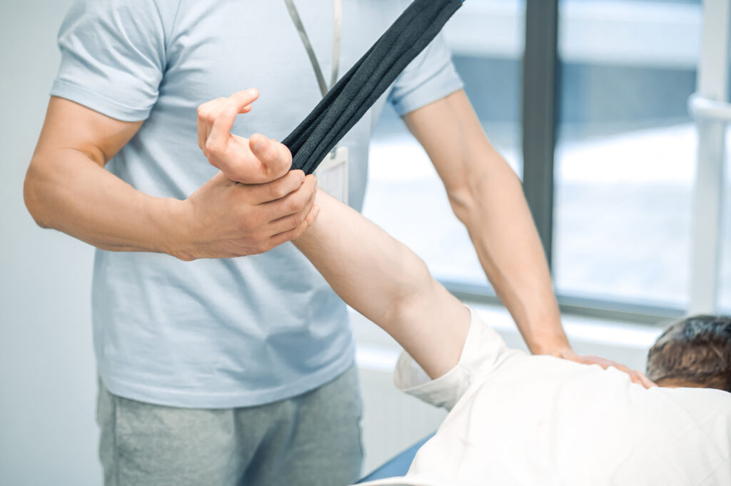 Male young patient having a session of arm hyperestension after trauma